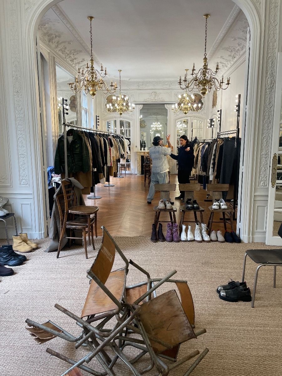 Fashion showroom in a Haussmannian apartment with brass chandeliers, clothing rails and shoes on wooden stools