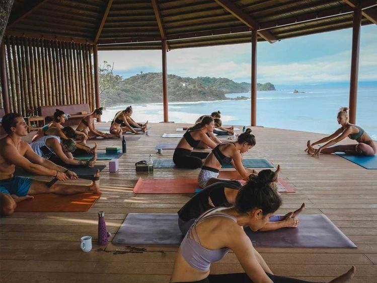 Yoga class on an open-air wooden deck overlooking the tropical sea at first light