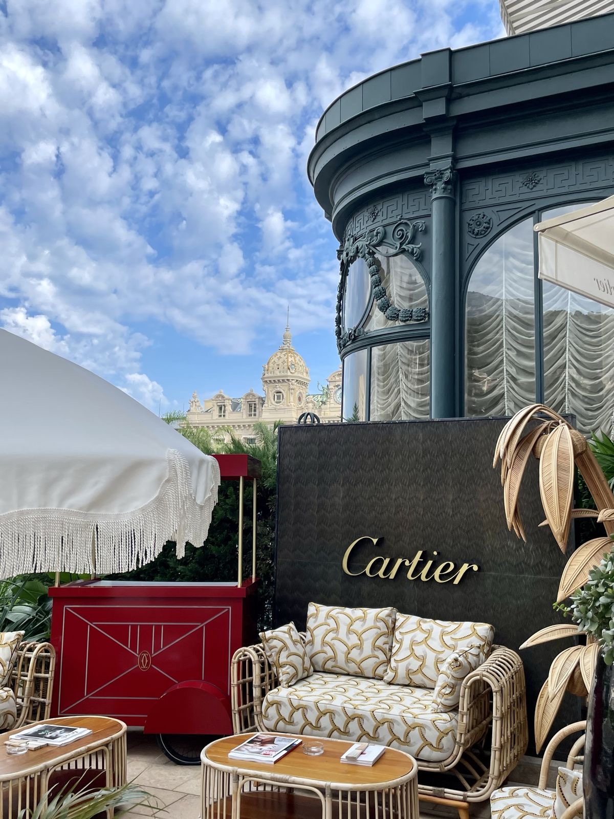 Cartier terrace in Monte-Carlo with rattan seating, fringed parasol and the Casino dome beyond