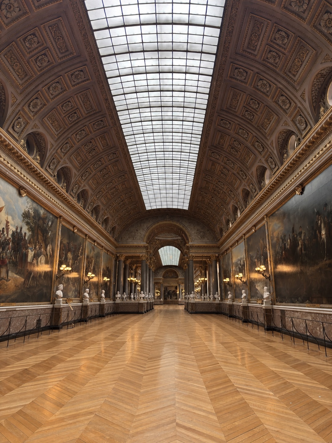 Gilded gallery of the Château de Versailles with parquet floors, glass ceiling and historic paintings