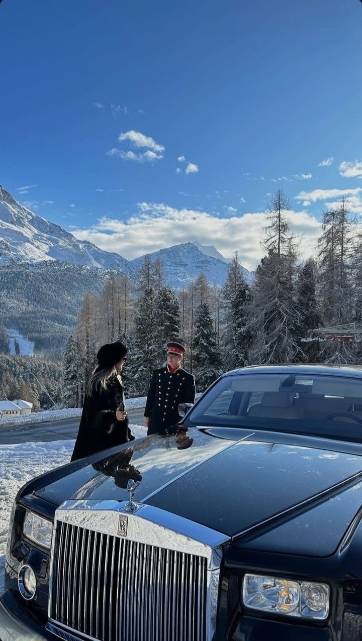 Rolls-Royce and a hotel doorman waiting on a snowy alpine road beneath the peaks