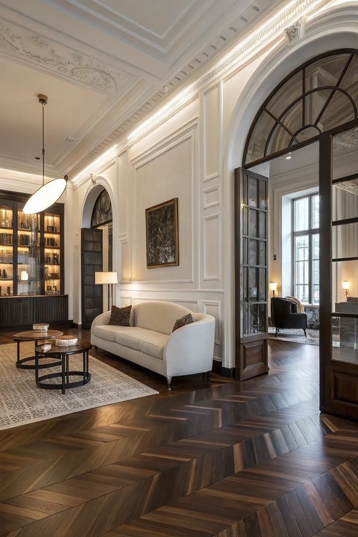 Haussmannian salon with moulded ceilings, herringbone parquet and an arched glass door onto the next room