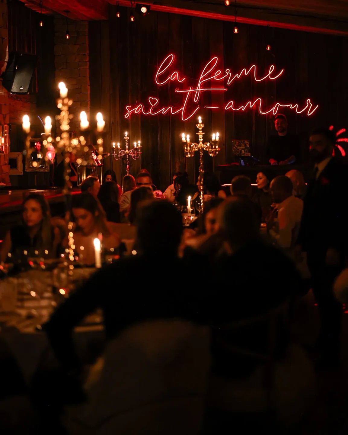 La Ferme Saint-Amour restaurant in Courchevel, candlelit dining room beneath a glowing red neon sign